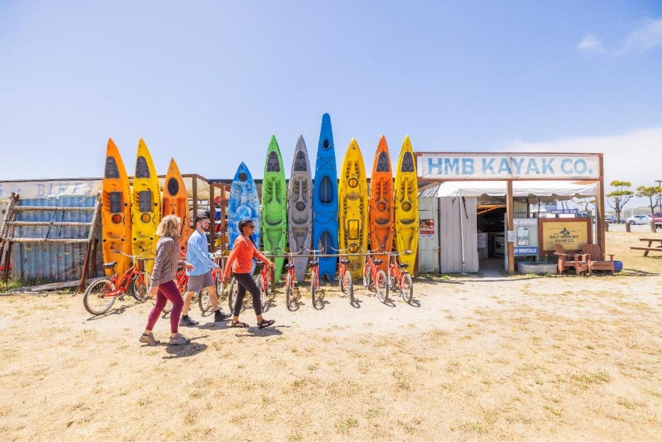 people walking to Half Moon Bay Kayak Company on the beach