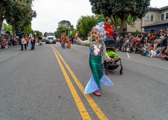 Child Mermaid Walks in Parade with Family